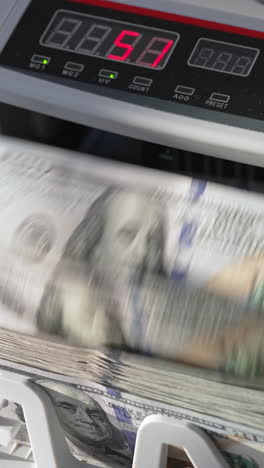 automatic cash machine for bank operations. modern device counting one hundred dollar bills. close up. vertical video