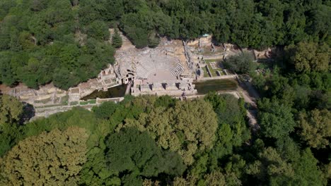 ancient roman amphitheater and buildings amidst lush greenery in butrint archaeological park in albania, aerial view