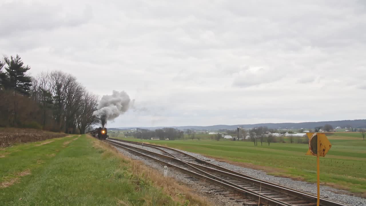 An Approaching Steam Passenger Train Blowing Smoke and Steam on a Cloudy Day