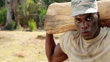 Fit-man-carrying-heavy-wooden-log-while-exercising