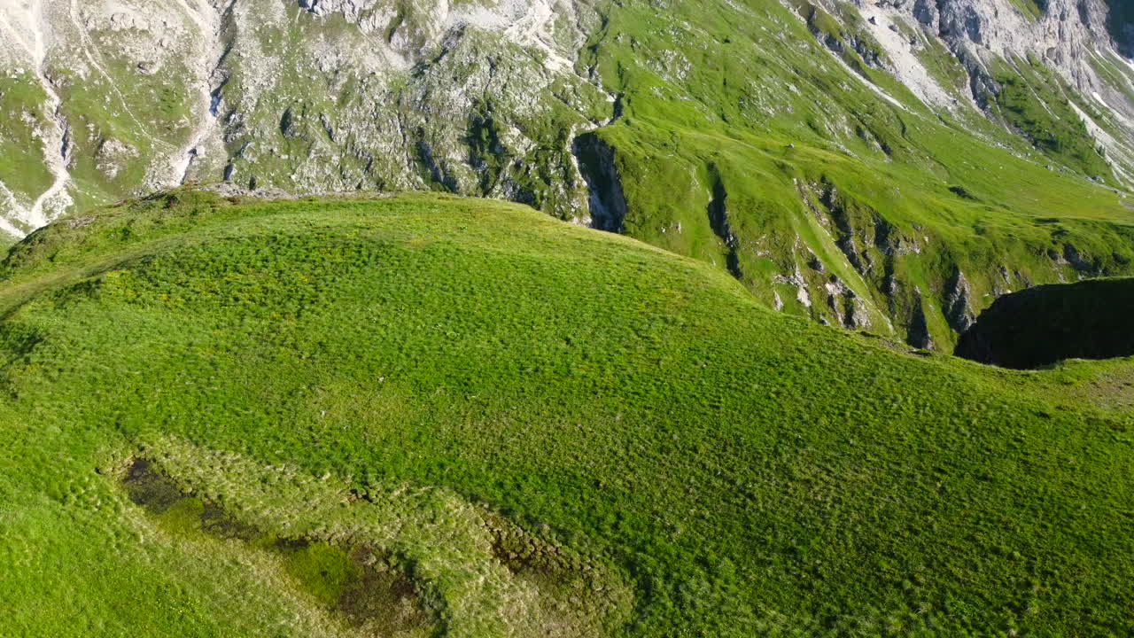 paisaje aéreo en cámara lenta de exuberante pradera verde en la cordillera de los dolomitas en un día de verano