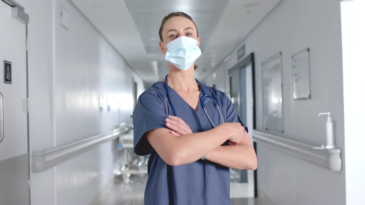 retrato de una feliz doctora caucásica con máscara facial en el pasillo, cámara lenta