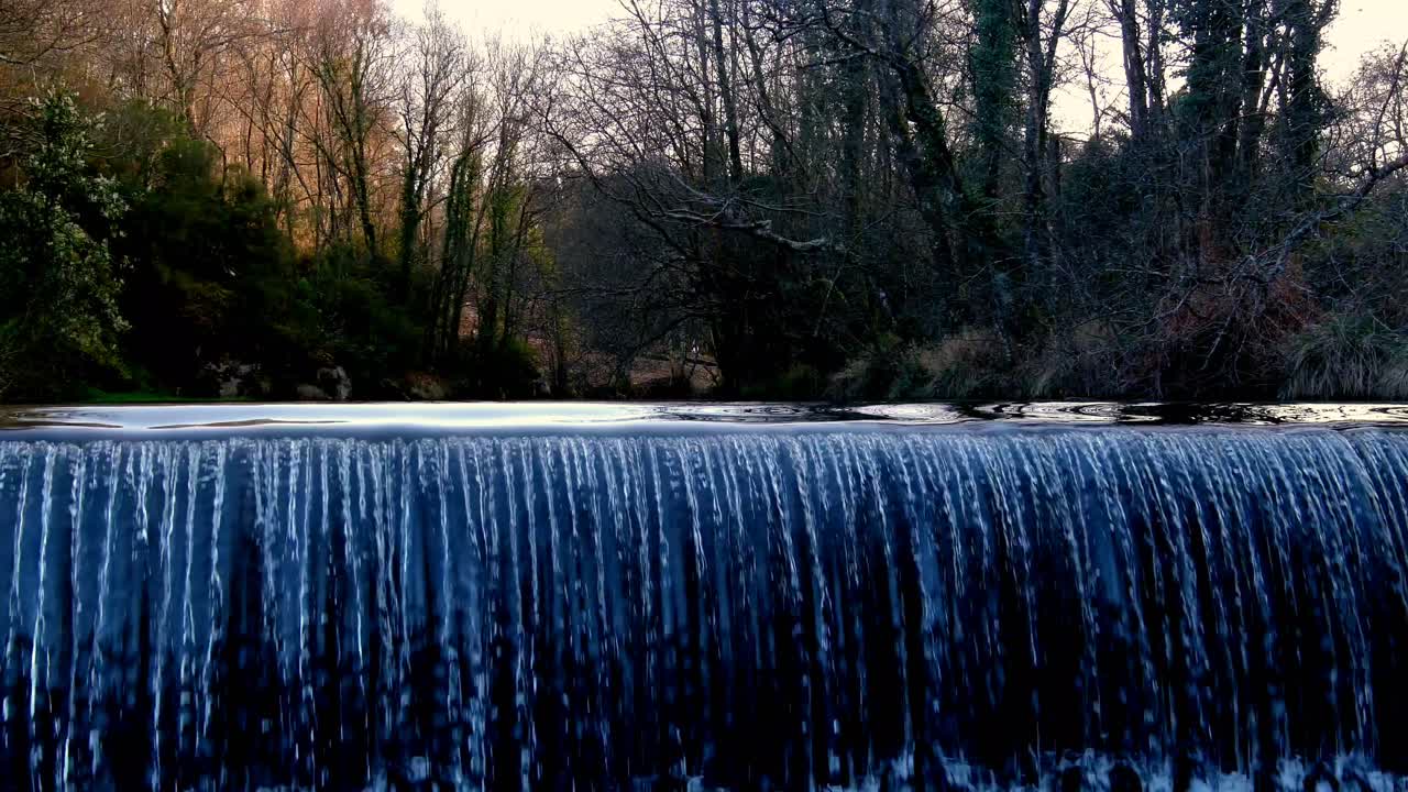 백그라운드에서 가을 숲 나무와 코 루나 스페인의 작은 전환 댐을 흐르는 강