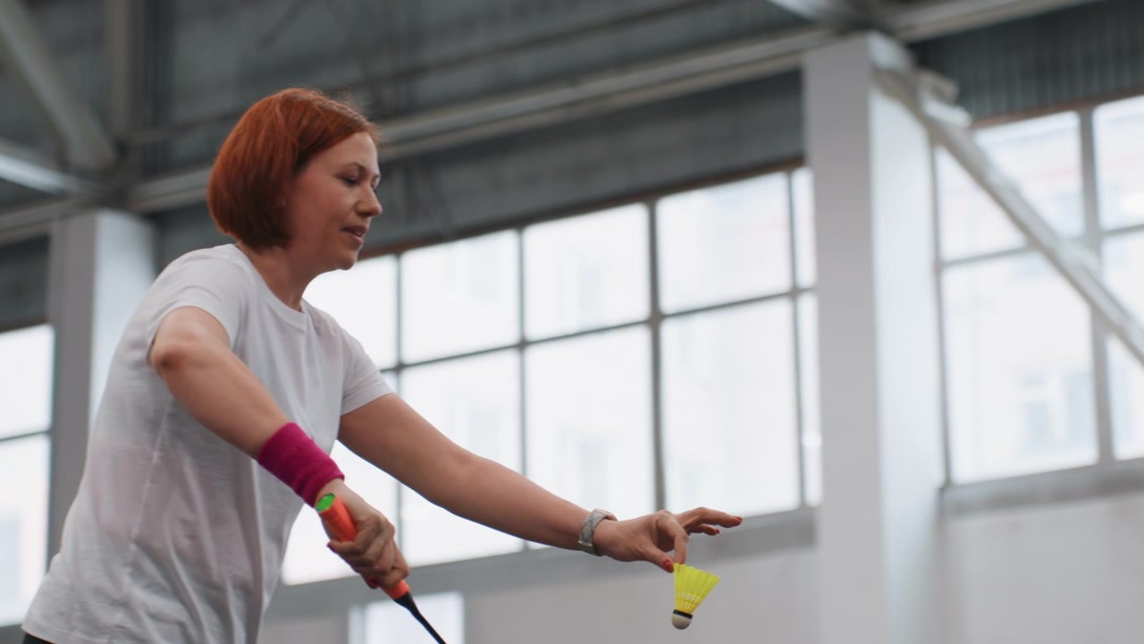 Indoor badminton practice white player executing powerful smashes and precise drives, intense footwork, concentrated expression, wristband accent, bright gym windows, focused training