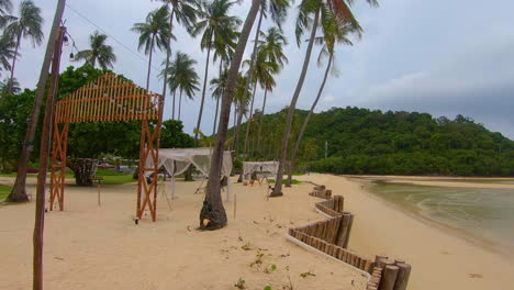cámara lenta | inclinarse hacia abajo desde las palmeras hasta el resort de playa en tailandia