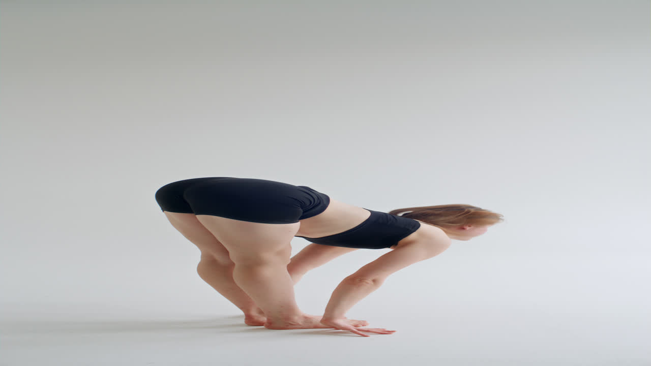 Junge Frau dehnt sich in stehender Vorwärtsbeuge in einem minimalistischen Studio