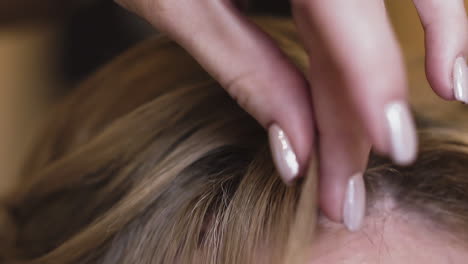 blonde woman with stylish manicure touches hair in room