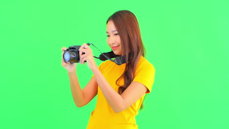 a pretty young woman, against a solid background, holds her camera out in front of her to get a steady panorama