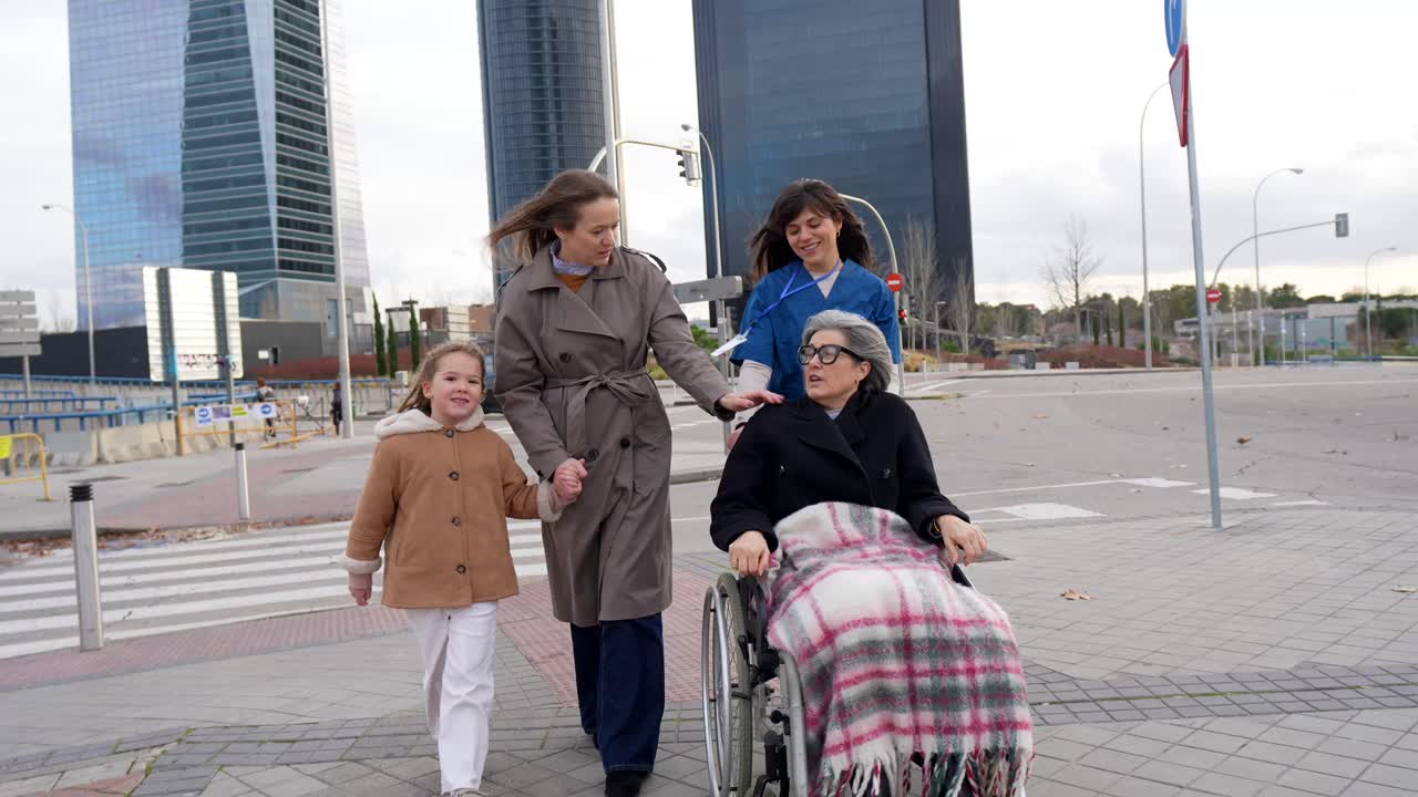 Famiglia e caregiver che camminano in città con un'anziana in sedia a rotelle