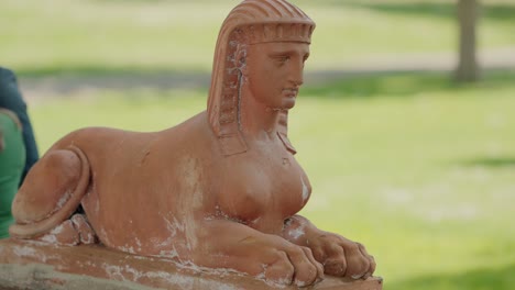 terracotta sphinx statue in a green park setting on a sunny day