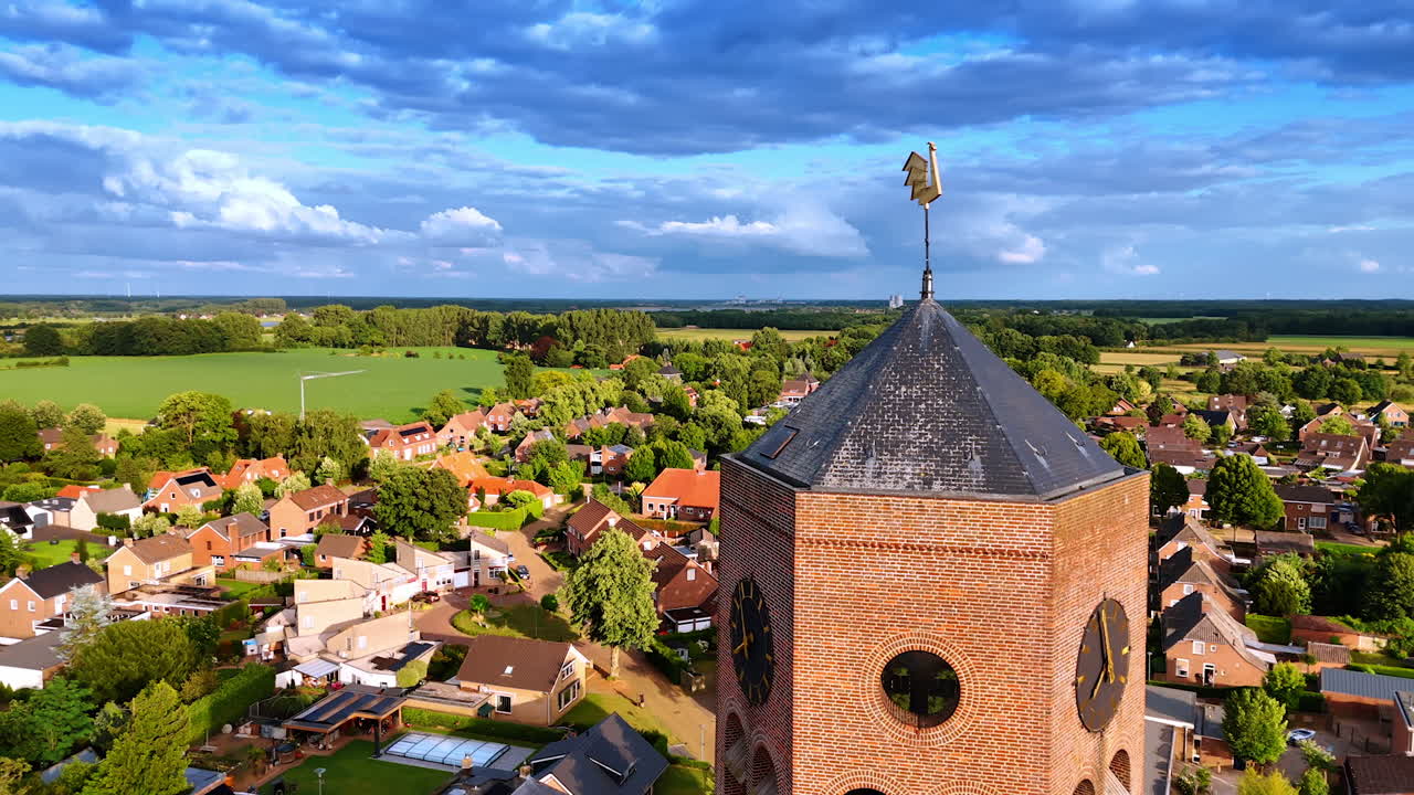 Aerial view of Dutch town with tall brick church tower. Drone view of a Dutch town with a tall brick church tower surrounded by houses and green fields