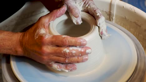 close up of the potter's hand shaping and molding clay on a turning wheel