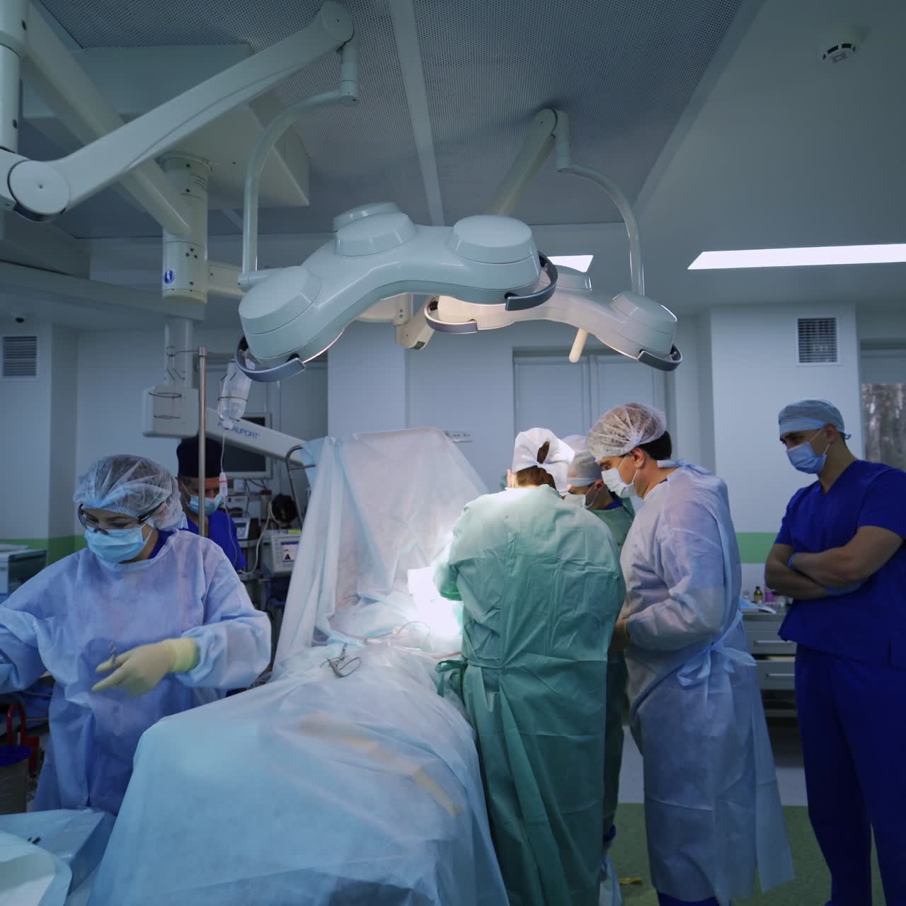 Big surgery team performing operation in well-equipped surgical theatre. Assisting nurse passing the metal instrument to the professionals