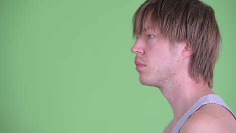 profile view portrait of caucasian man thinking and looking around shot against green studio background