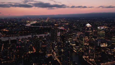 Vista-Panorámica-De-La-Gran-Ciudad-Por-La-Noche,-Paisaje-Urbano-Contra-El-Cielo-Crepuscular.-Vuela-Sobre-El-Distrito-Urbano-Moderno.-Londres,-Reino-Unido