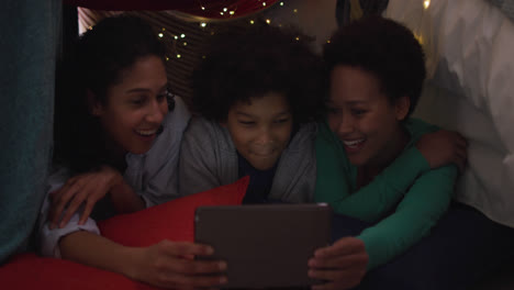 mixed race lesbian couple and daughter using tablet lying in bedroom camp