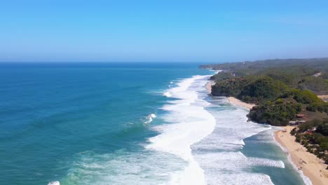 Foamy-waves-hitting-coastline-of-Indonesia,-aerial-drone-view