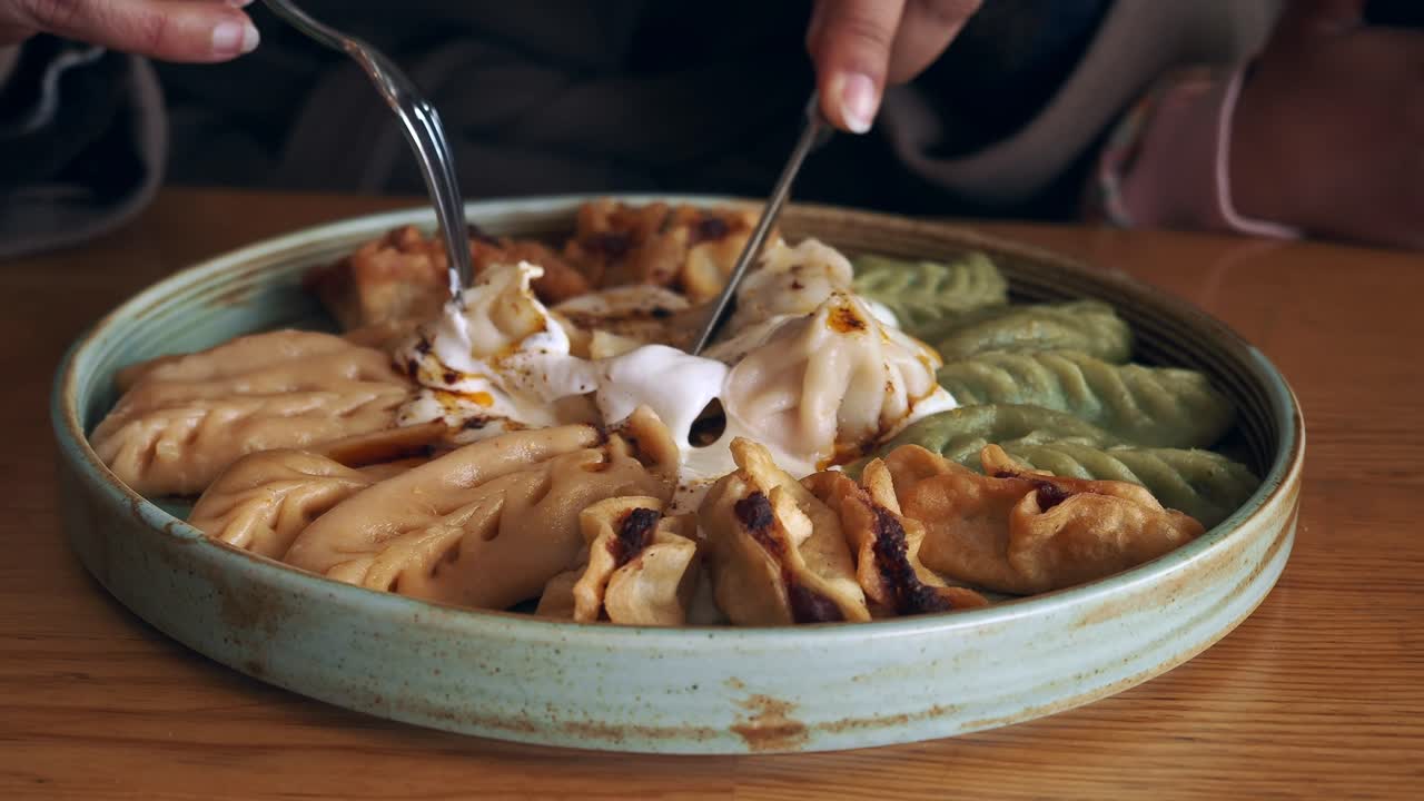 Close-up of Hands Cutting and Serving Delicious Dumplings with Sauce