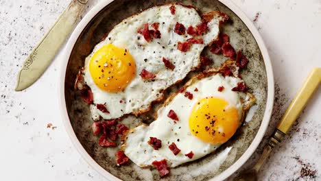 two fresh fried eggs with crunchy crisp bacon served on rustic plate