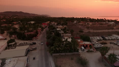 High-Drone-Footage-revealing-setting-sun-over-the-sea-in-Cabo-San-Lucas,-Mexico
