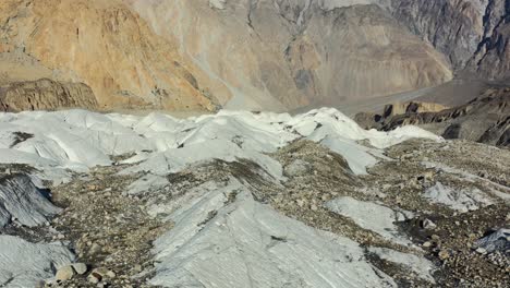 Drone-Aéreo-Volando-Bajo-Y-Lento-Sobre-El-Glaciar-Passu-En-Hunza-Pakistán-Durante-Un-Día-De-Verano-Con-Mucha-Suciedad-Y-Barro-Con-Vistas-A-Las-Grandes-Montañas