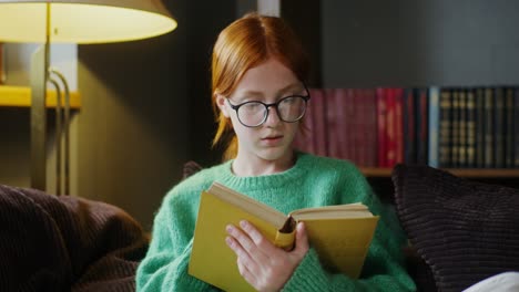 Una chica leyendo un libro en casa.