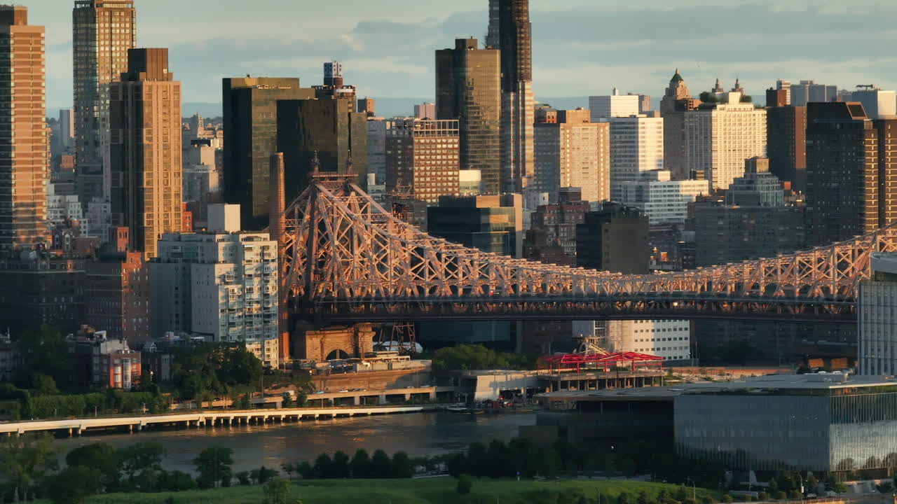 Aerial view of the Queensboro Bridge at sunrise. Shot along the East River with Roosevelt Island and Manhattan in the background