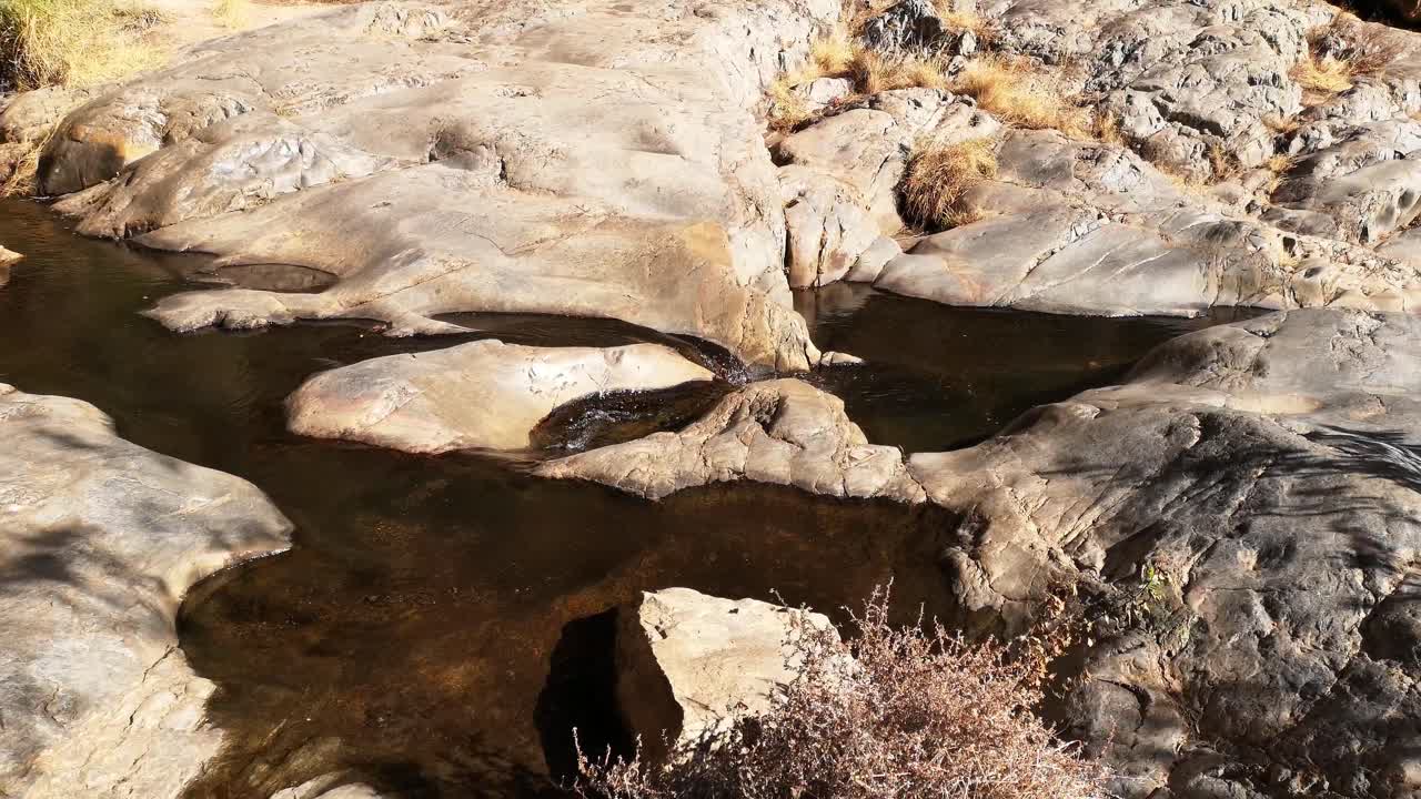 Water flowing out of small pond over rocks in desert area