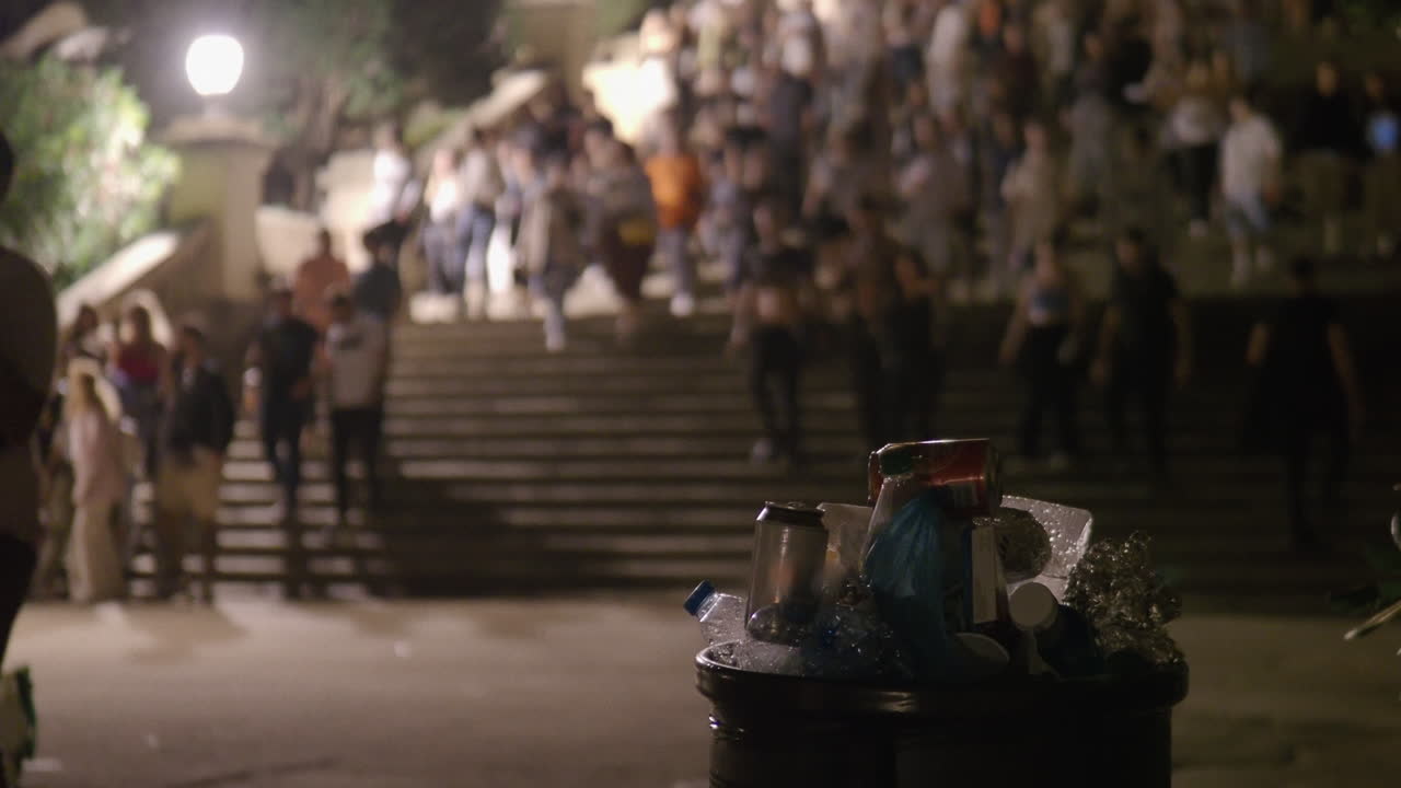 Night Crowd Walking Down Stairs with Trash Can in Foreground