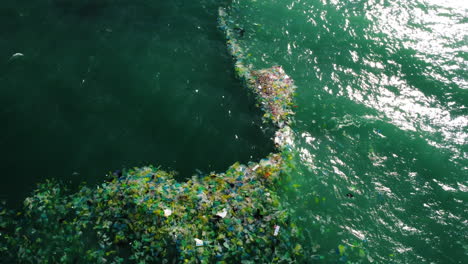 Antenne-Von-Oben-Nach-Unten,-Eine-Schicht-Plastikmüll-Aus-Dem-Meer,-Die-Sich-Zwischen-Zwei-Strömungen-Angesammelt-Hat