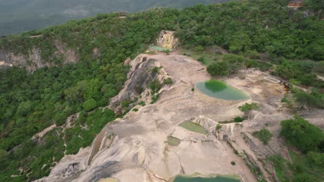 Aerial-fly-away-of-natural-swimming-pools-in-granite-above-a-cliff-in-a-tropical-rainforest