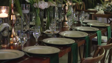 elegant banquet table design at a wedding reception, with glassware, plates and natural flowers