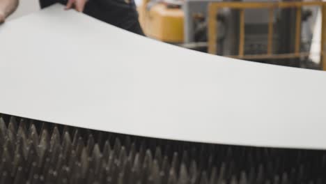 workers putting sheet of metal on pointy maneuverable platform of cnc machine