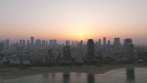 Tel-Aviv-coastline-at-sunrise-with-beautiful-calm-waters-of-The-Mediterranean-Sea,-Waterfront-hotels-and-light-sun-flare