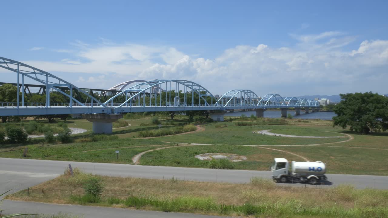 Water Tanker Truck Driving In The Road With Aqueduct Bridge In Osaka, Japan. - wide shot