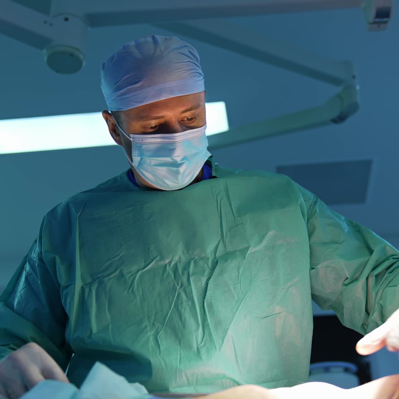 Surgeon pumping fat with surgical tool from patient's body. Doctor in medical mask doing medical procedure for losing weight. Front view