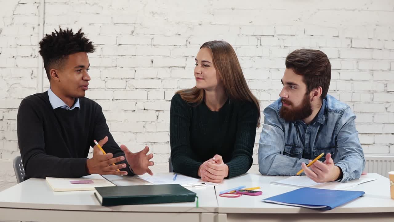 Young african guy explaining something to his colleagues. multi ethnic group of people working together. Happy diverse group of
