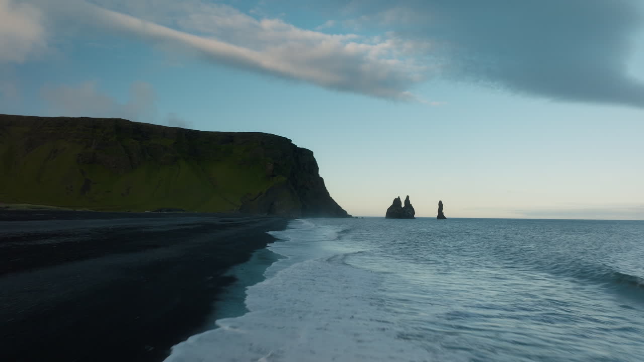 Low altitude aerial flight across Reynisdrangar Beach in Iceland during sunset, with cliffs in the distance. Part 1.