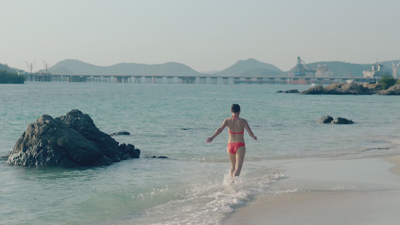 머리에  ⁇ 을  ⁇ 은 여자가 리조트에서 바다 파도에서 달리고 있습니다.