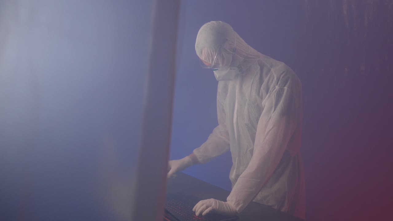 보호복, 안면 마스크, 고글을 착용한 실험실 작업자는 열정과 헌신으로 노트북 작업을 합니다.