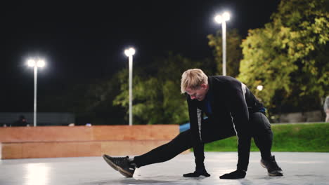 hombre rubio deportivo estirando las piernas antes de entrenar en el parque por la noche 1