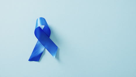 video of blue cancer awareness ribbon on blue background with copy space