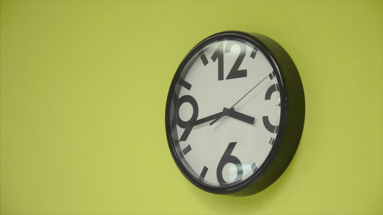 Black wall clock on a lime green wall