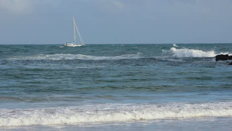 pleasure boat floats on the waves of the green sea on the background of coast and beaches in cascais