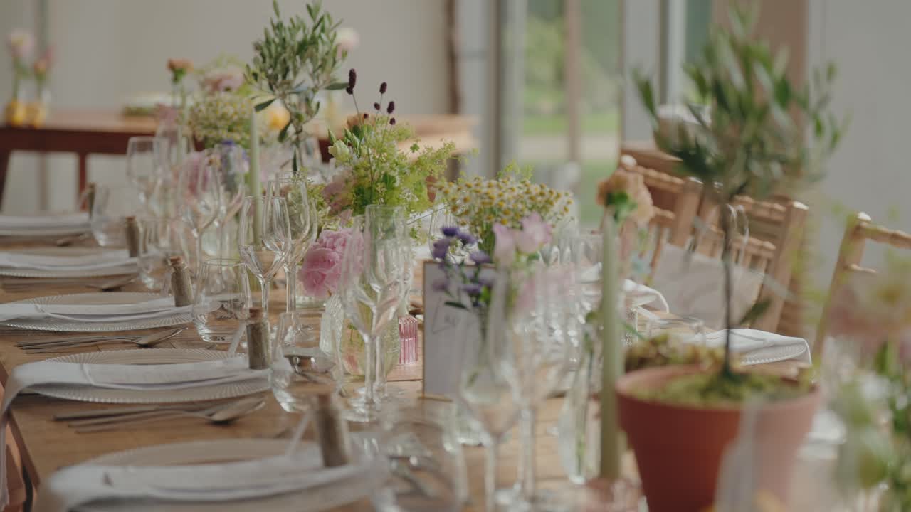 Long wooden table set for wedding reception with flowers glassware