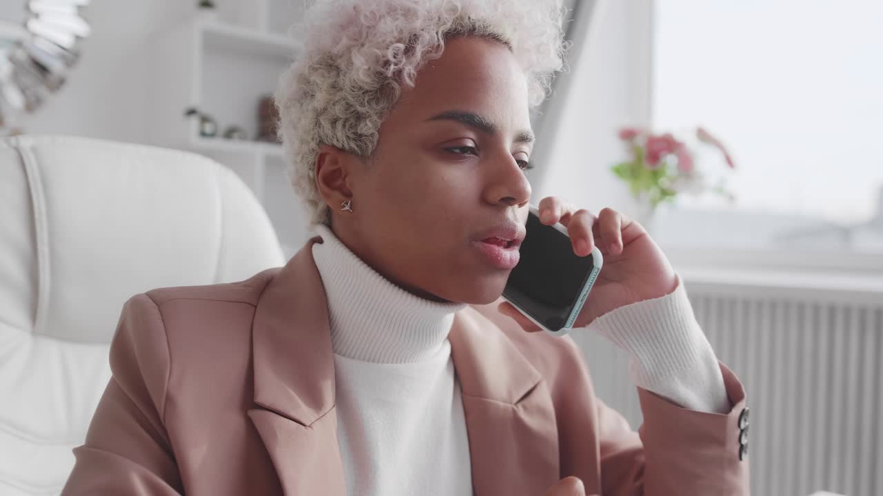 African american business woman talking on phone using laptop at home office