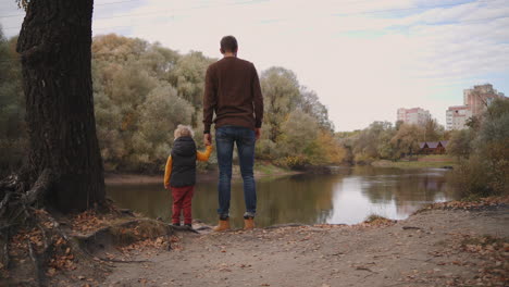 el joven padre se está comunicando con el hijo pequeño en el bosque hablando sobre la naturaleza y mostrando el hermoso lago en el bosque la familia descansa los fines de semana y vacaciones