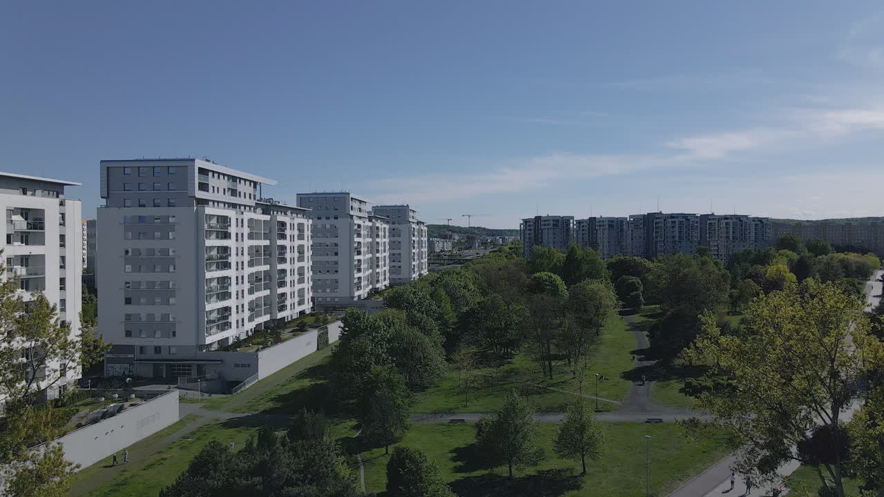 Park with green trees close to tall buildings, bicycle paths and concrete pavements in a modern park, Gdansk Zaspa, poland