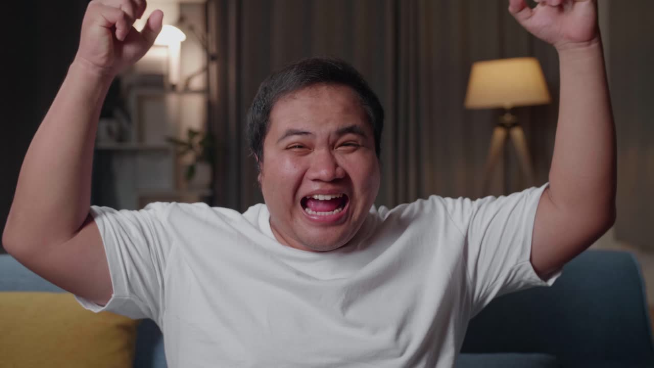 Asian Fat Man Watches Tv And Celebrating While Sitting On A Couch At Home