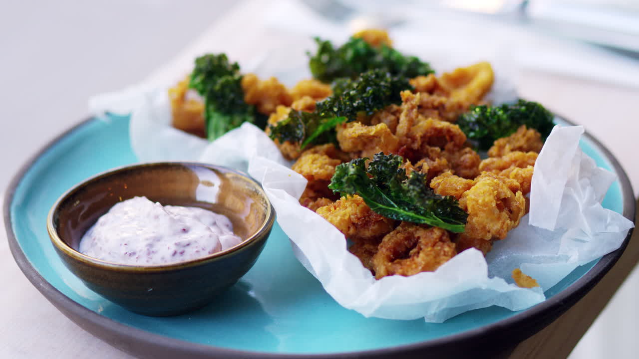 Plate of fried squid, kale and sumac mayo pulls out of focus